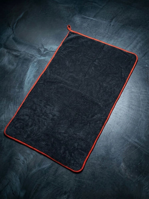 Black towel with red trim on a textured dark surface